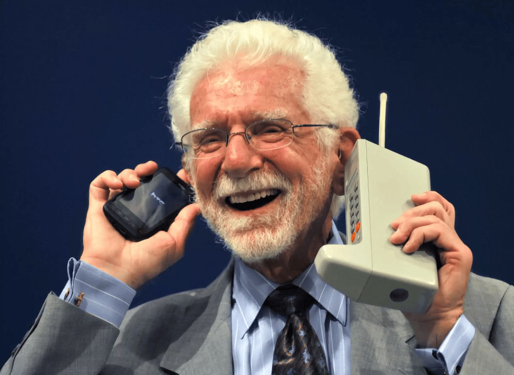 Photon of Martin Cooper holding the DynaTac 8000X along with a modern cell phone.